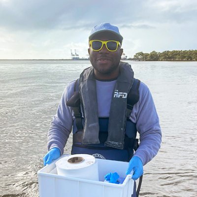 a man stands in water holding a plastic container